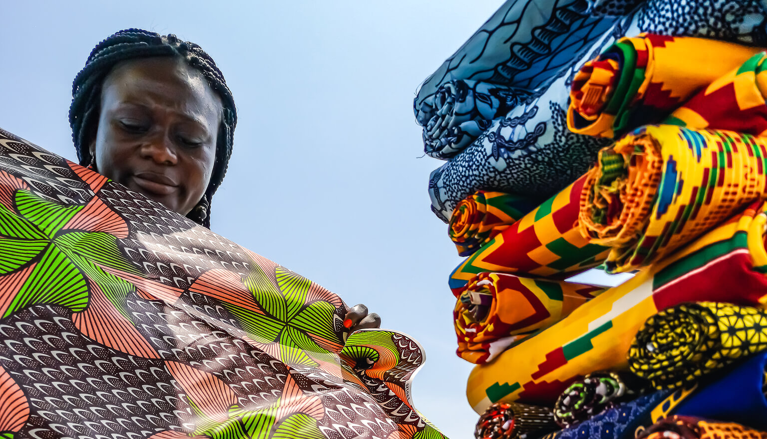 Woman folding traditional Ghanian textiles.