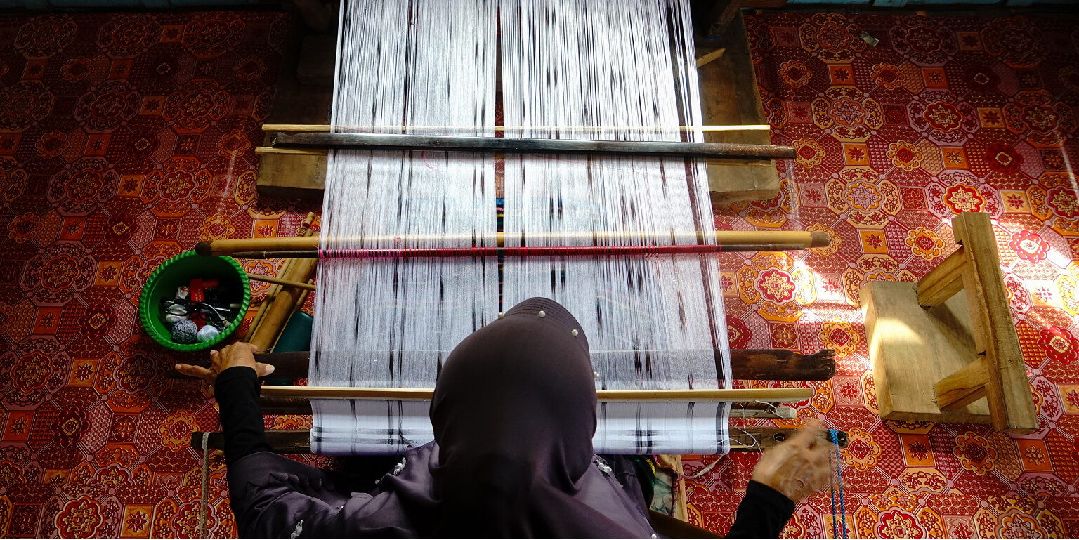 Image of a lady weaving from above.